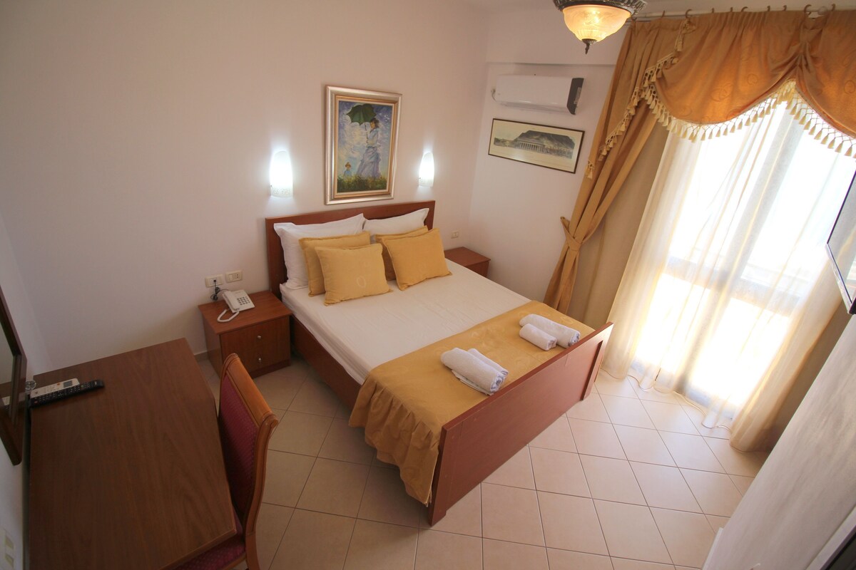 Ein Hotelzimmer mit Bett, Nachttisch, Lampe und einem Bild an der Wand.