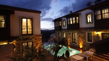 A courtyard with a swimming pool, stone walls, and outdoor seating.