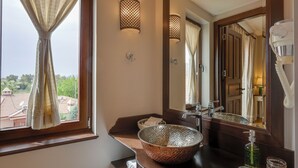 Une salle de bain avec un grand miroir, un lavabo en cuivre et une fenêtre avec des rideaux.