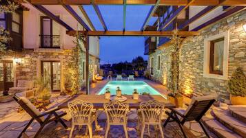Zona de piscina con muros de piedra, mobiliario exterior y una estructura de pérgola.