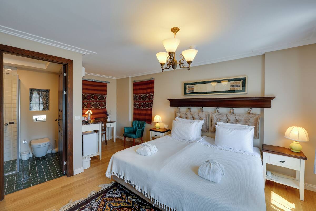 A hotel room with a large bed, a desk, a chair, and a bathroom.