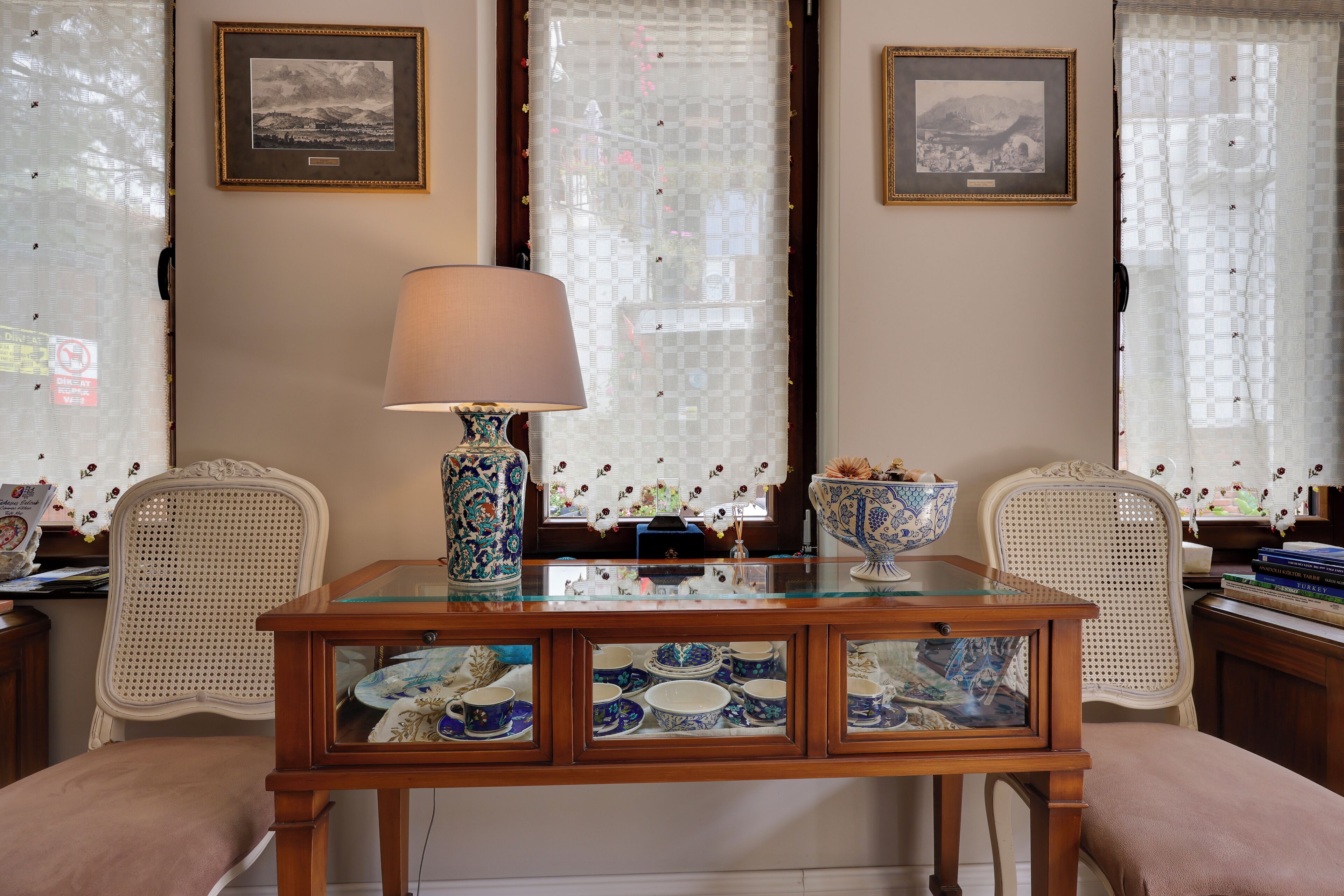 A dining area with a glass-top table, two chairs, a lamp, and a decorative bowl.