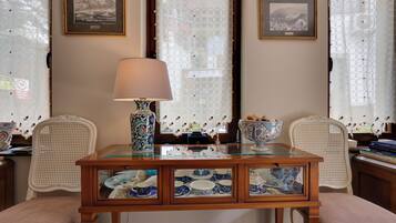A dining area with a glass-top table, two chairs, a lamp, and a decorative bowl.