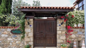 Un mur de pierre avec une porte en bois, des plantes en pot et une enseigne.