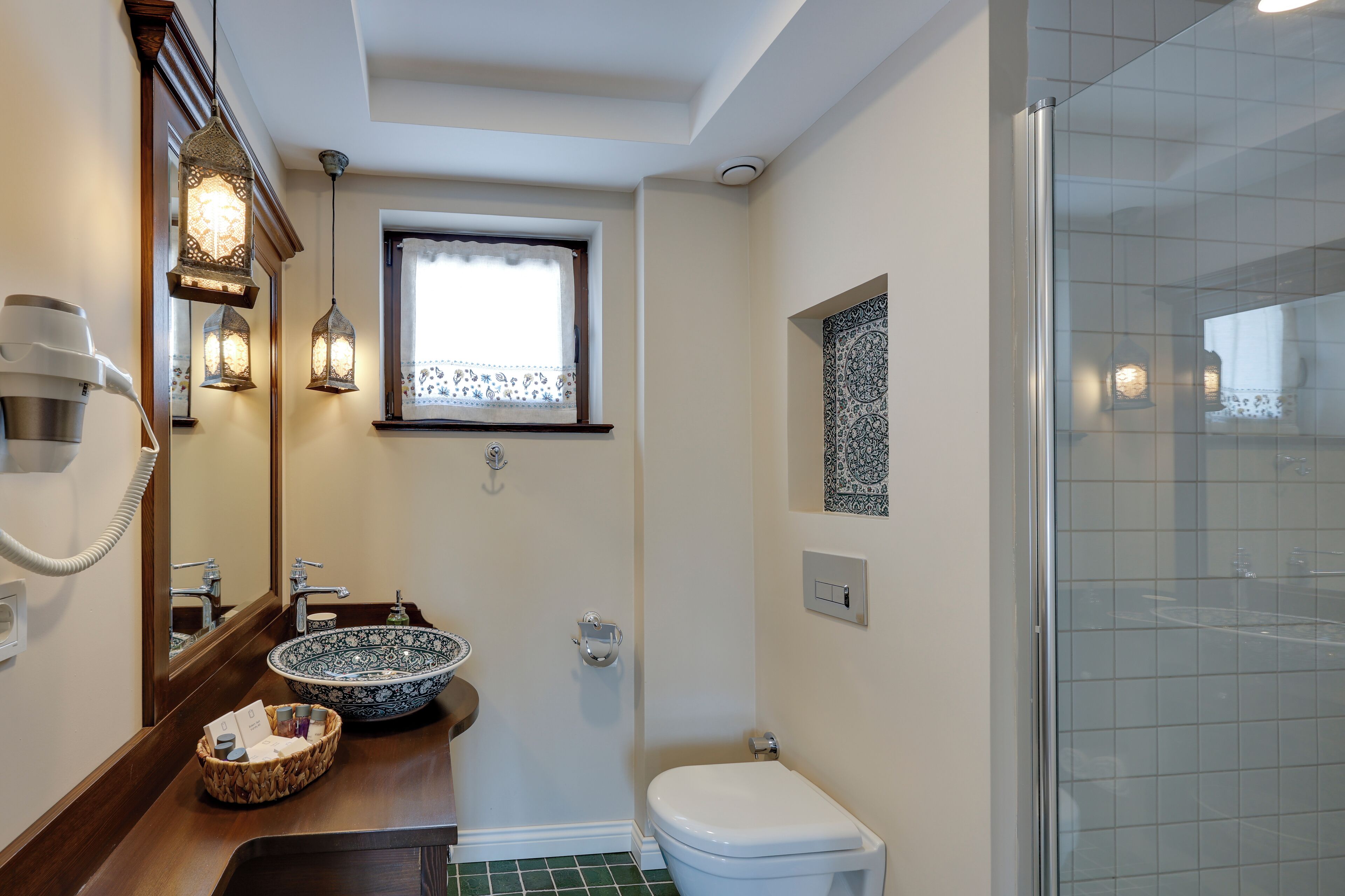 Un baño con un espejo grande, un lavabo con un cuenco decorativo, un inodoro y una zona de ducha.