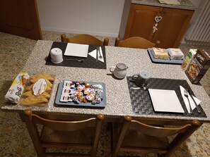 A dining table set with plates, cutlery, and various food items, surrounded by wooden chairs. - B&B Buscemi (Pistoia)