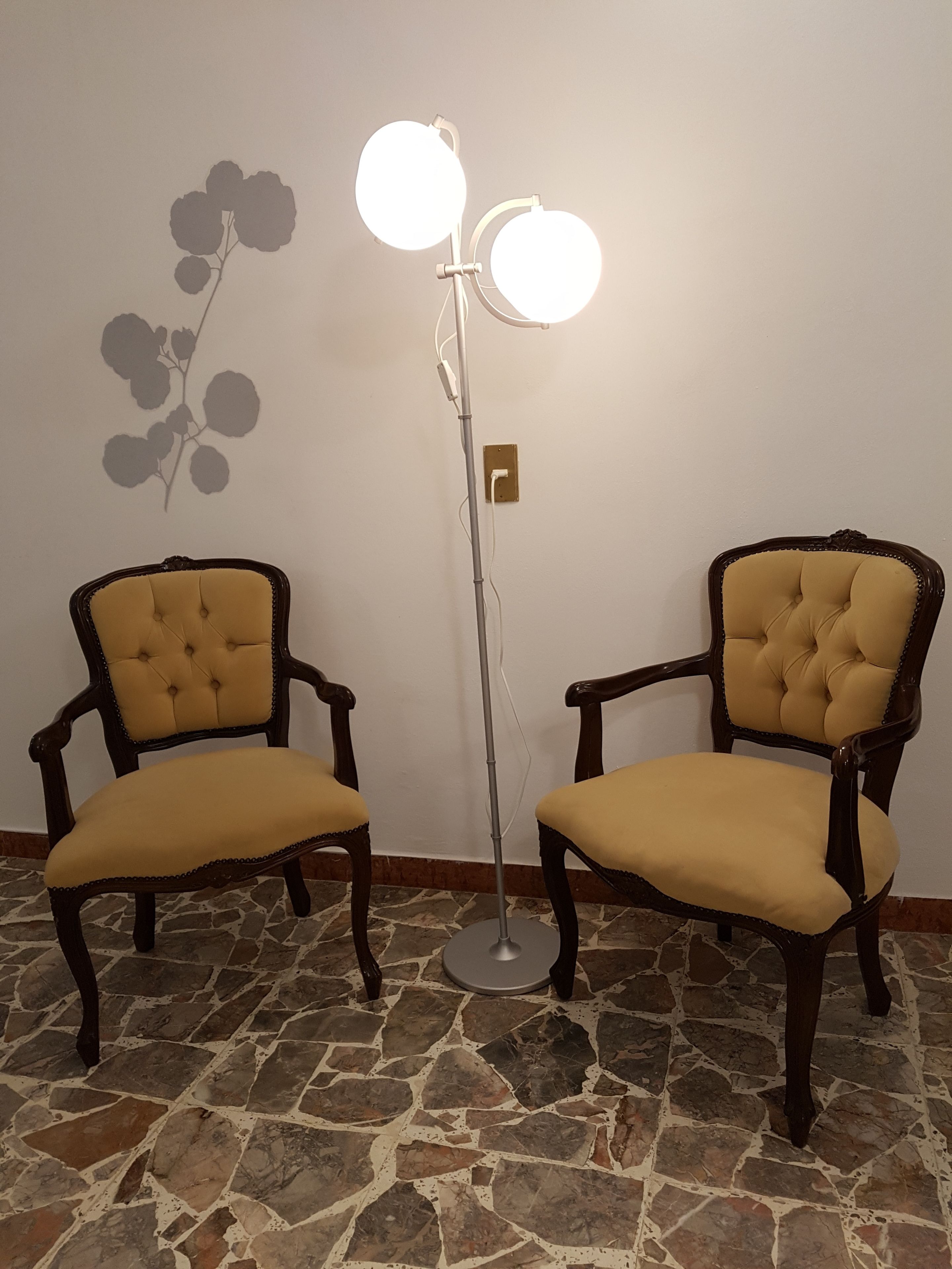 Two upholstered chairs with wooden frames and a floor lamp with three lights.