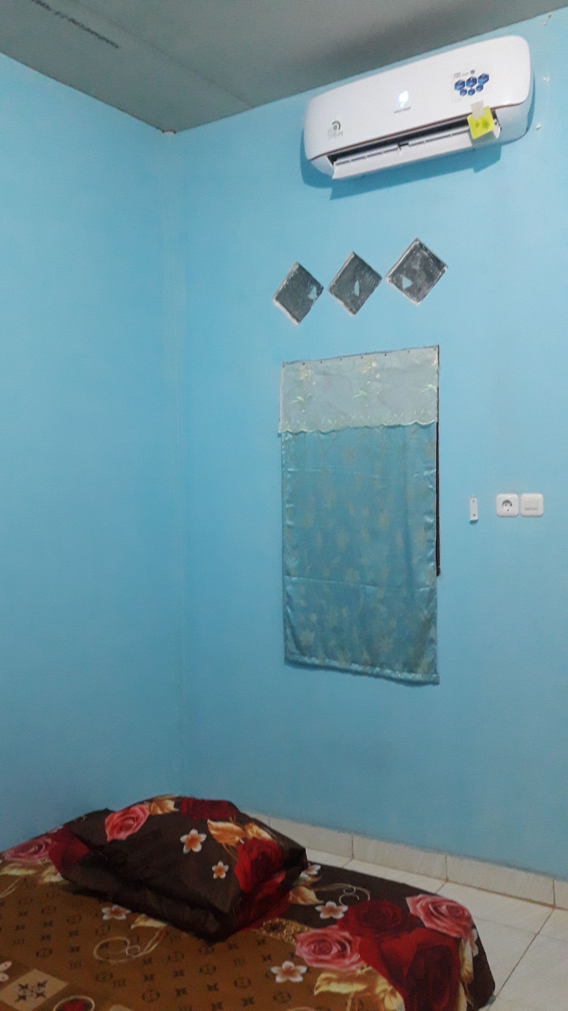 Une chambre comprenant un lit, un climatiseur, un interrupteur fixé au mur et une prise de courant.