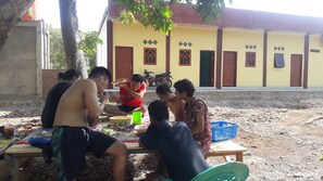 A group of people sitting at an outdoor table with various food items and utensils. - Penginapan asidik (Bira)