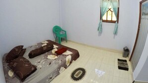Una habitación pequeña y bien iluminada con una cama, una ventana con cortinas, una silla y un cesto de basura.