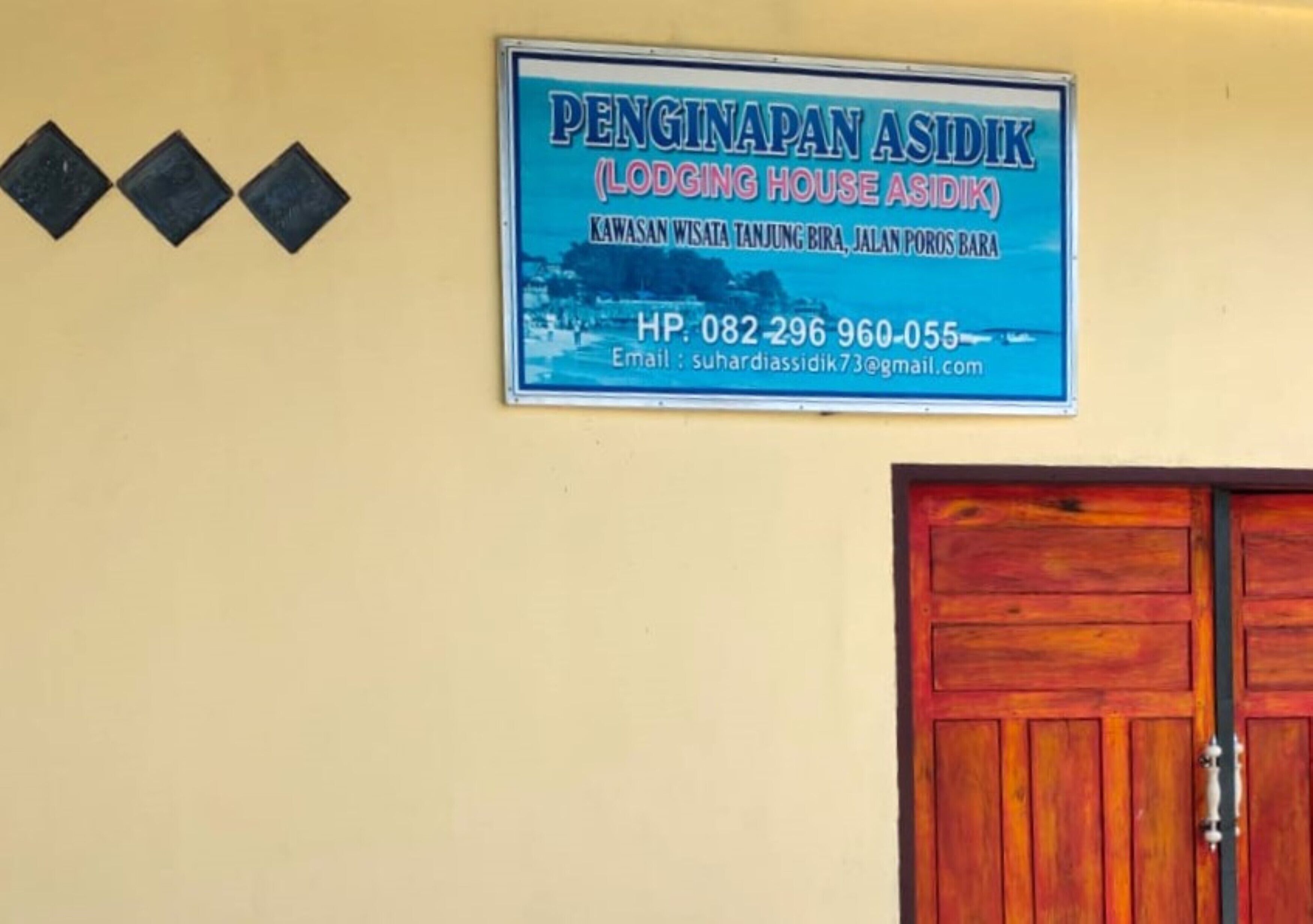 A sign for Penginapan Asdik (Lodging House Asdik) with contact information.