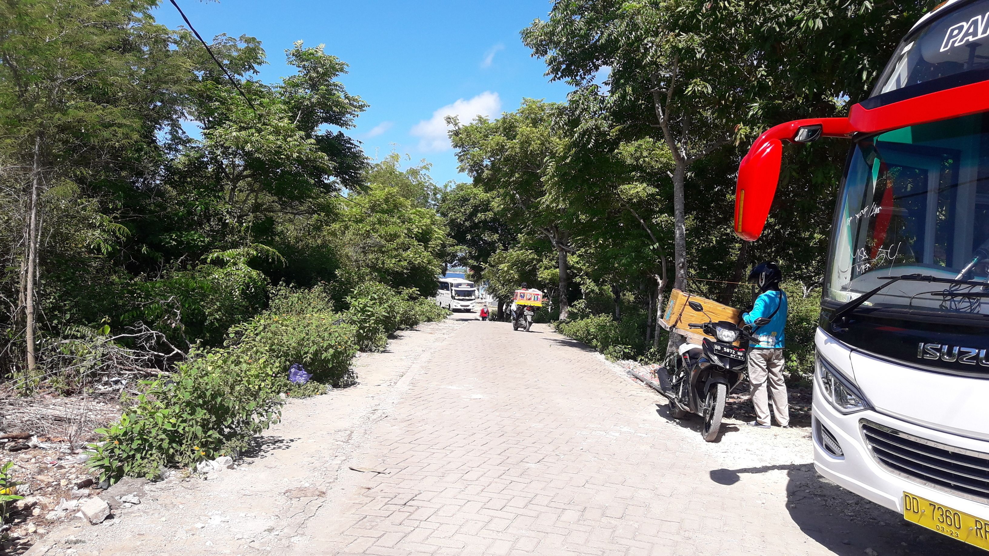 A paved road with vehicles and a motorcycle carrying a large box.