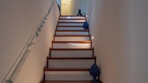 Una escalera con peldaños de madera y barandillas de vidrio, que conduce a un piso superior.