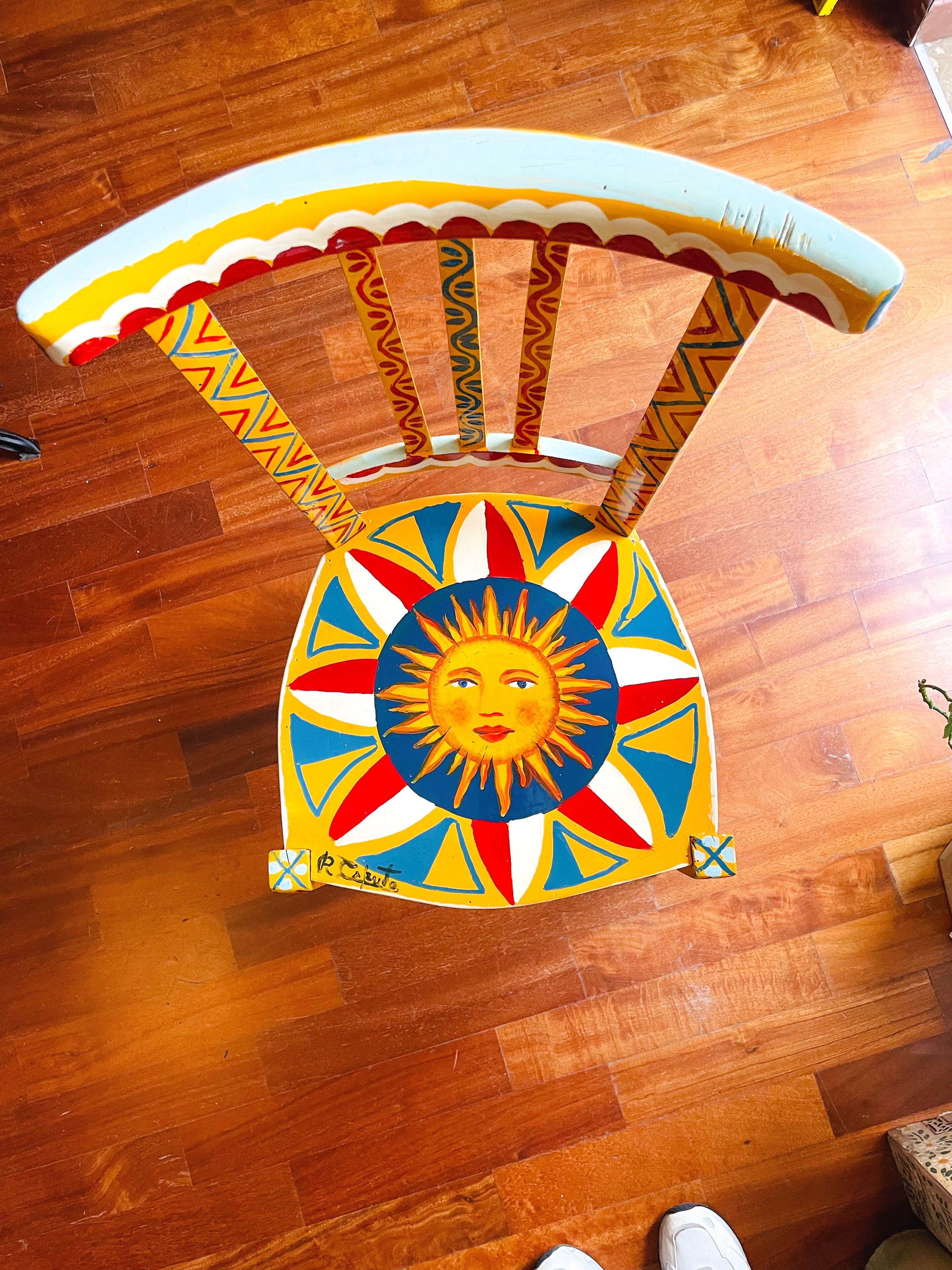 A colorful chair with a sun design on the seat and a patterned backrest.