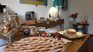 Una mesa de buffet con diversos alimentos, como un pastel grande, fruta y salsas.