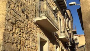 Una calle estrecha con edificios de piedra, balcones y un cielo azul despejado.