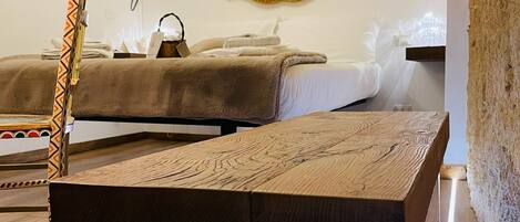 A modern room with a wooden table, a mirror, and a bed with a beige blanket.