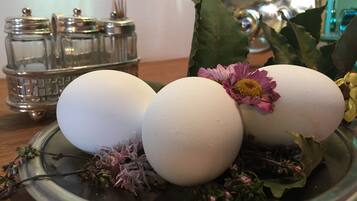 Tres huevos blancos en un plato con flores y hierbas.