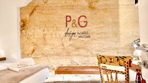 Una habitación con pared de piedra, una cama con cabecero blanco, una silla de madera y una toalla sobre la cama.