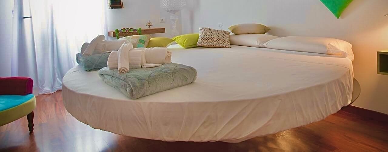 A circular bed with a white mattress, surrounded by pillows and towels.