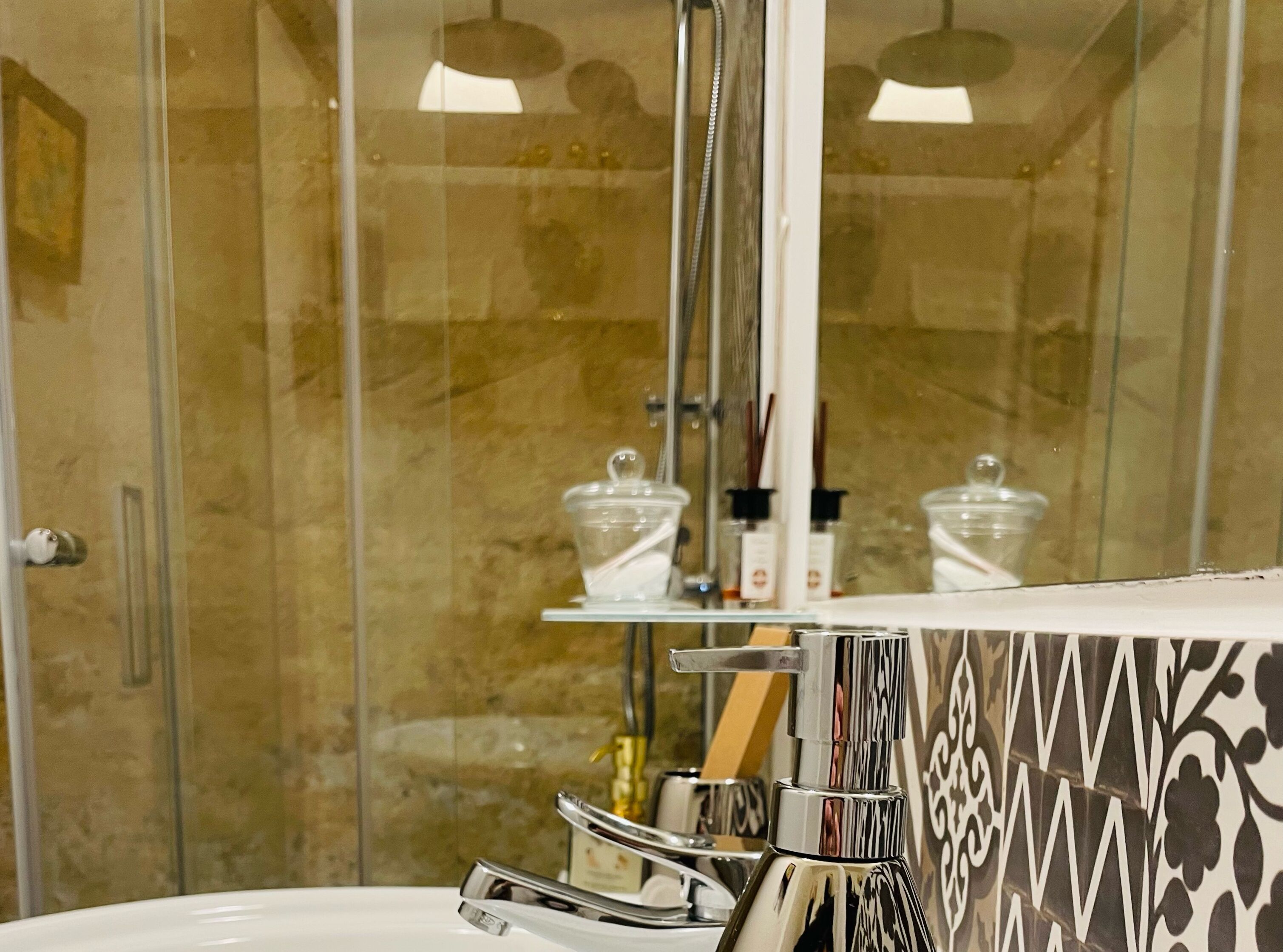 A bathroom with a glass shower enclosure, a white sink, and a mirror above the sink.