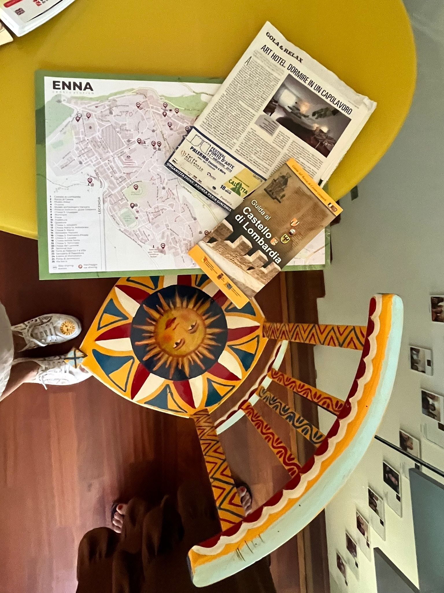 A map of Enna, a guide to Castello di Lombardia, and a newspaper article on a table.