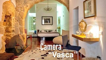A room with a stone archway, a chandelier, a bed, and a cowhide rug.