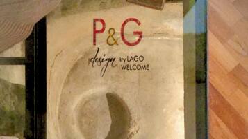 A person sitting on a bench with a large poster in the background reading "P&G design by LAGO WELCOME".