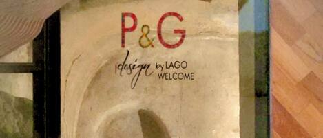 A person sitting on a bench with a large poster in the background reading "P&G design by LAGO WELCOME".