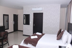 Habitación de hotel con cama, escritorio, silla y unidad de aire acondicionado en la pared.