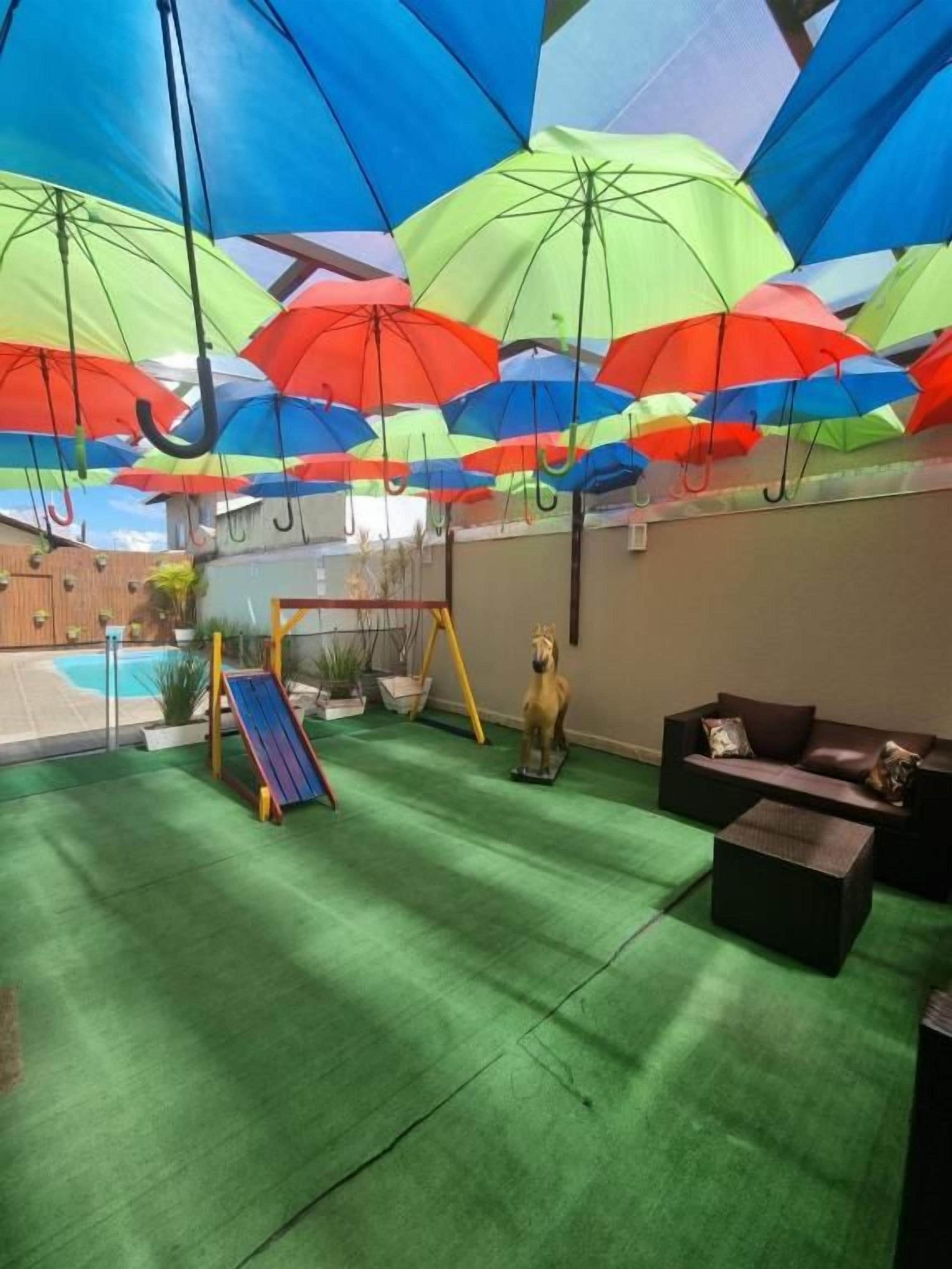 A covered outdoor area with a swing set, a statue, and a pool in the background.