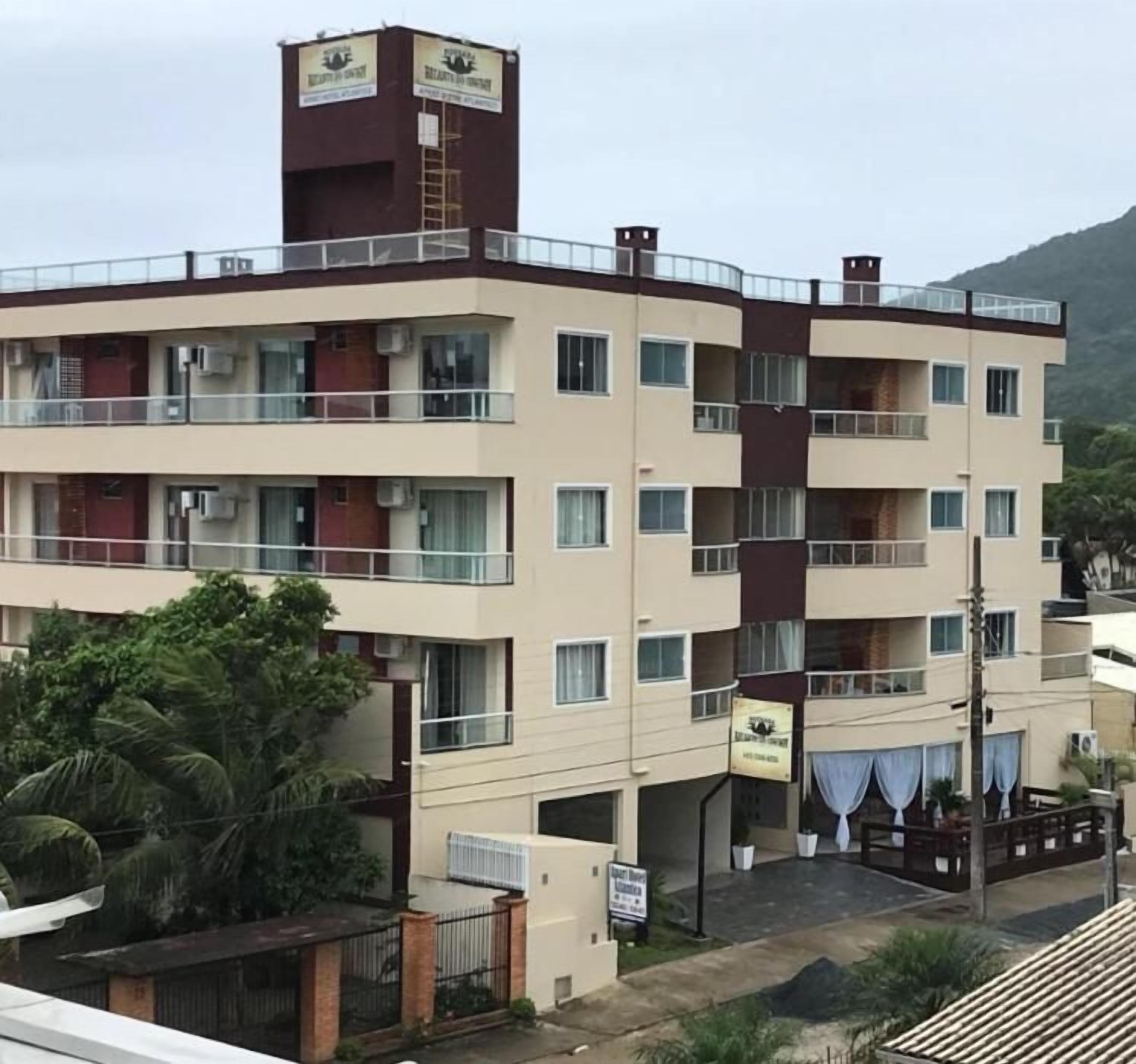 Un hotel de varios pisos con balcones, unidades de aire acondicionado y un letrero que indica un restaurante.