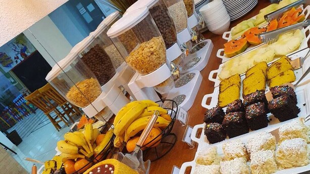 Un bufé con diversas opciones de comida, incluyendo frutas, postres y bocadillos.