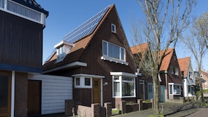 Una casa residencial con techo inclinado, paneles solares y garaje.