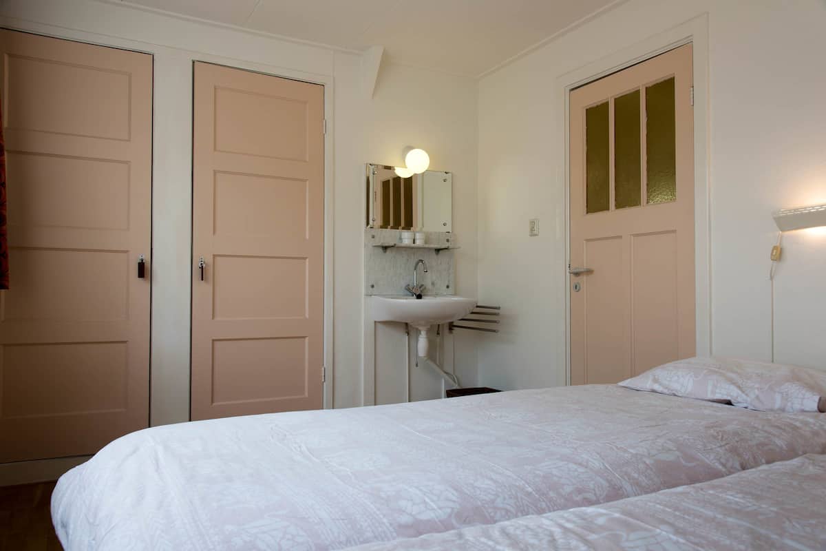 Ein Schlafzimmer mit einem Bett, einem weißen Waschbecken und einem Spiegel darüber.