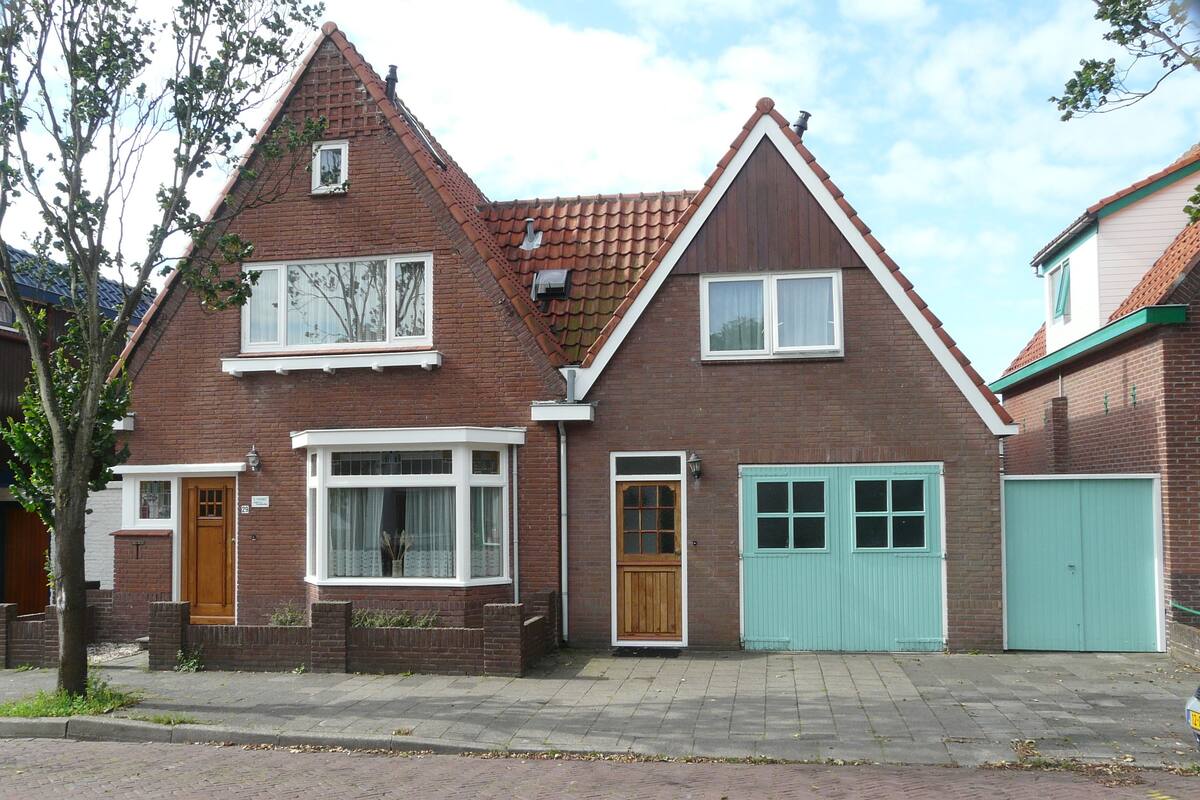 Ein zweistöckiges Haus mit Ziegelverkleidung, einem Satteldach und einer Garage.