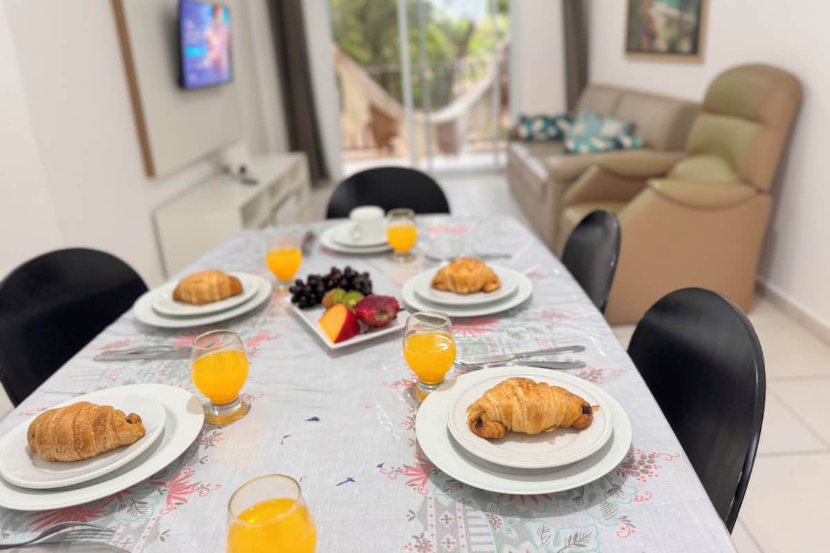 A dining table set with plates of food, glasses of orange juice, and a fruit platter.