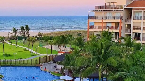 A resort with a swimming pool, palm trees, and a view of the ocean. - Beach Living, Frente mar, 400m do B Park (Aquiraz)