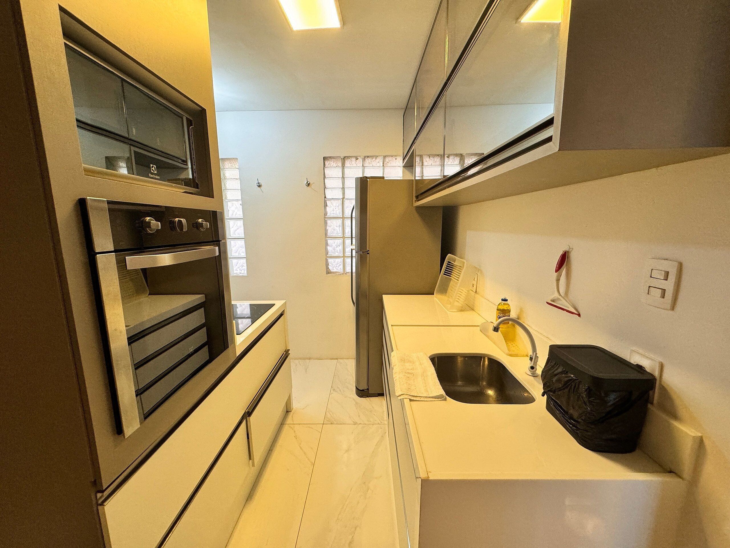 A compact kitchen with a built-in oven, a sink, and a refrigerator.