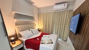 A hotel room with a bed, a TV, an air conditioner, and a window with curtains. - Beach Living, Frente mar, 400m do B Park (Aquiraz)