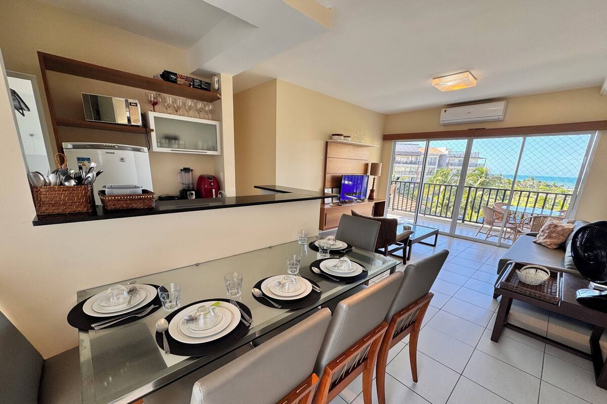 A modern kitchen with a dining area, a balcony with a view, and a TV.