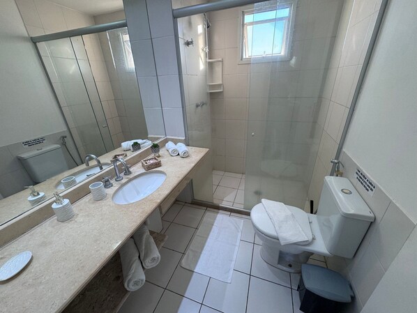 Baño con lavamanos, espejo, toallero y zona de ducha.