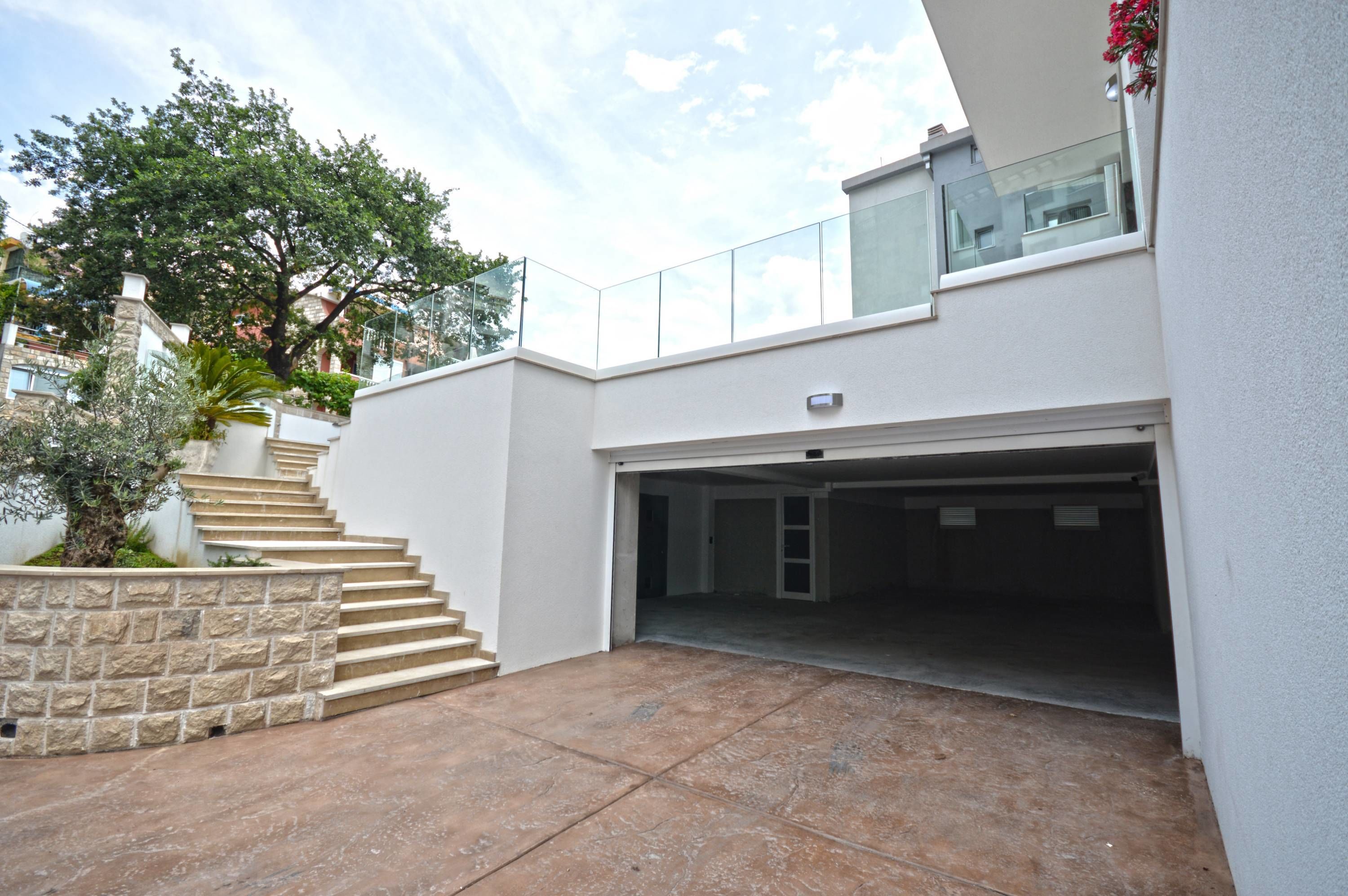 A modern building with a garage, stone steps, and a tree.