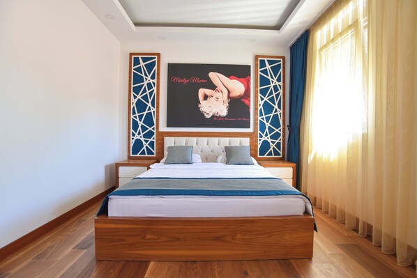Un dormitorio moderno con una cama grande, un cartel enmarcado en la pared y una ventana con cortinas.