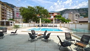 Un área de piscina en la azotea con sillones de descanso y barandilla de cristal.