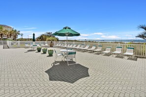 Relax in comfort with ocean views from this inviting outdoor seating area, featuring lounge chairs and a shaded table.