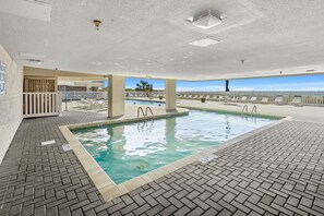 Swim laps in the pool surrounded by ocean views through the glass walls.
