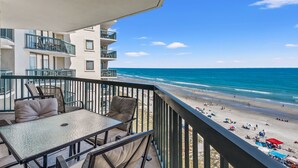 A balcony with a table and chairs overlooking a beach. - Ocean Bay Club Oceanfront Resort (North Myrtle Beach)