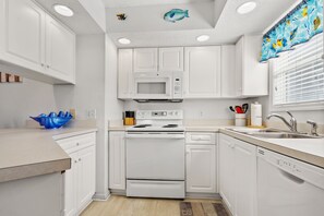 Kitchen features a central stove, microwave, and sink with a faucet.