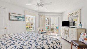 A bedroom with a bed, a ceiling fan, a television, a dresser, and a chair. - Shorehaven II Beach Resort (North Myrtle Beach)